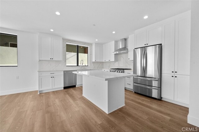 kitchen with wall chimney exhaust hood, white cabinetry, and appliances with stainless steel finishes