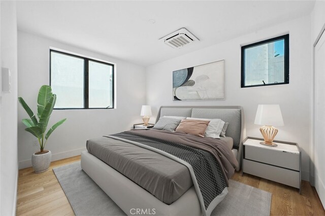 bedroom with light hardwood / wood-style flooring and multiple windows