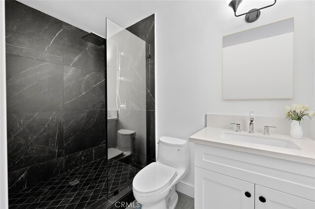 bathroom with a tile shower, vanity, and toilet