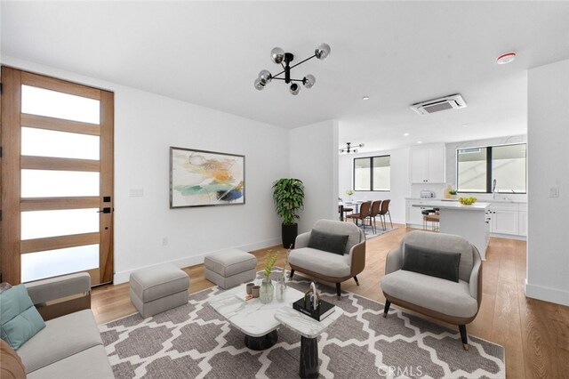 living room with sink, light hardwood / wood-style flooring, and a chandelier