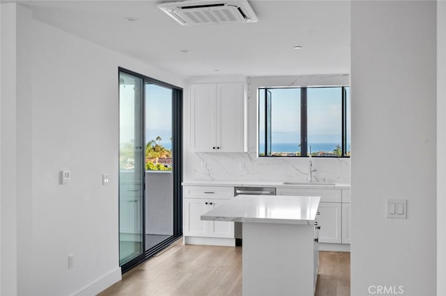 kitchen with a wealth of natural light, white cabinetry, light wood-type flooring, and sink