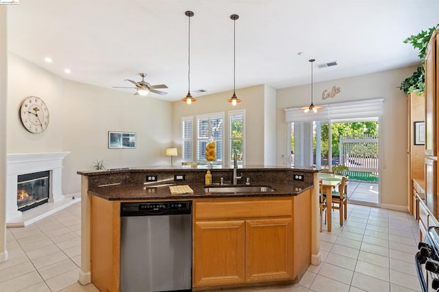 kitchen with ceiling fan, dishwasher, sink, an island with sink, and dark stone counters