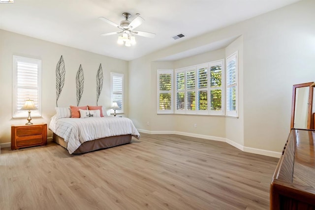 bedroom with ceiling fan, light hardwood / wood-style floors, and multiple windows