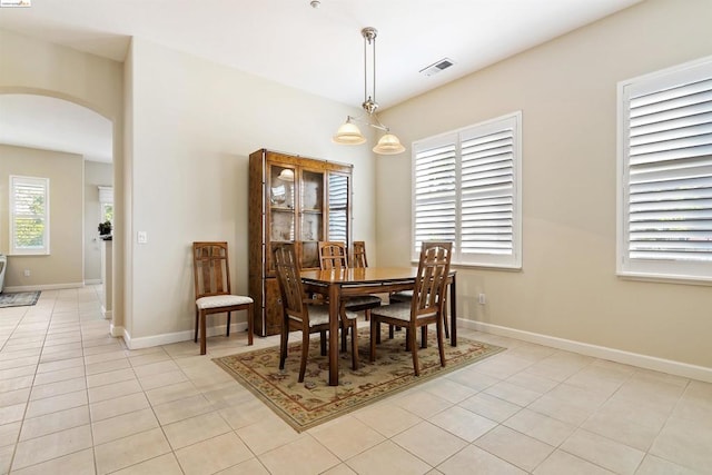 dining space with light tile patterned floors, a healthy amount of sunlight, and a chandelier