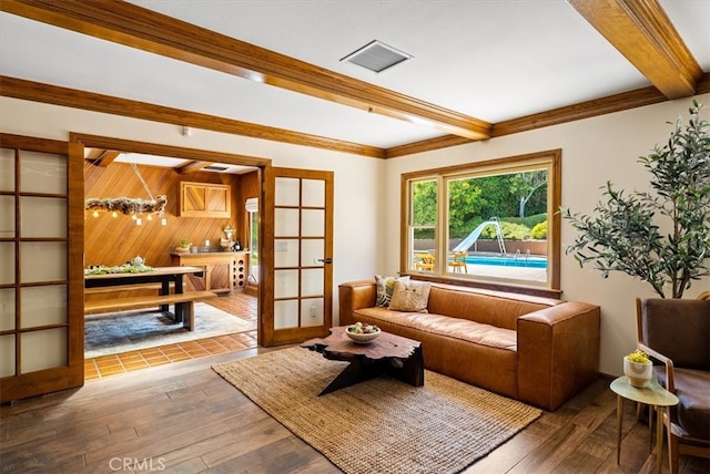 living room with beam ceiling, wood walls, hardwood / wood-style flooring, and french doors