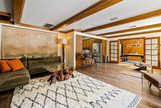 living room featuring wood-type flooring, french doors, beam ceiling, and ornamental molding