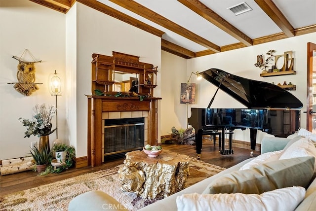 living room with a tiled fireplace, beamed ceiling, and hardwood / wood-style floors