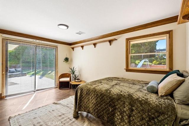 bedroom featuring wood-type flooring, crown molding, and access to exterior