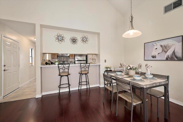 dining space featuring high vaulted ceiling and wood-type flooring