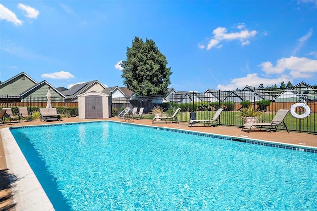 view of swimming pool with a patio and a storage shed