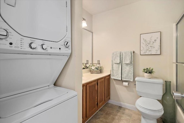 bathroom with vanity, stacked washer and dryer, and toilet