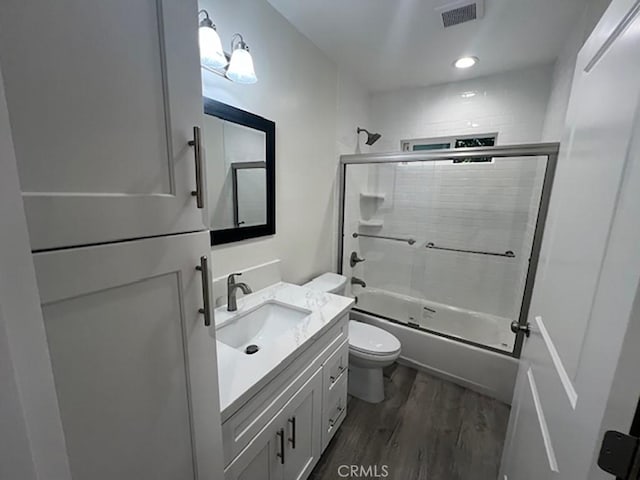 full bathroom featuring combined bath / shower with glass door, hardwood / wood-style floors, vanity, and toilet