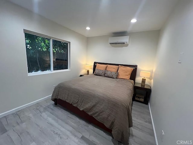 bedroom with light hardwood / wood-style flooring and a wall unit AC