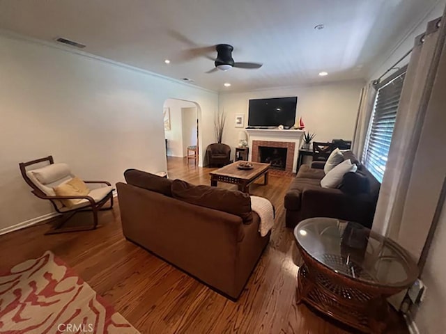 living room featuring hardwood / wood-style flooring, ceiling fan, and crown molding