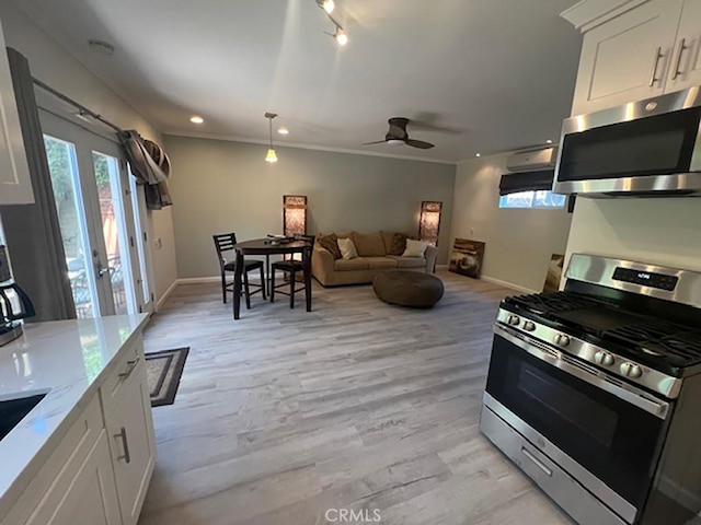 kitchen with ceiling fan, light stone countertops, light hardwood / wood-style floors, white cabinets, and appliances with stainless steel finishes