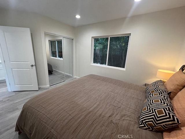 bedroom with light hardwood / wood-style floors and a closet