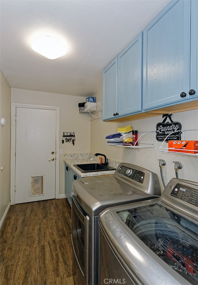 laundry room featuring sink, a textured ceiling, washer and clothes dryer, cabinets, and dark hardwood / wood-style floors