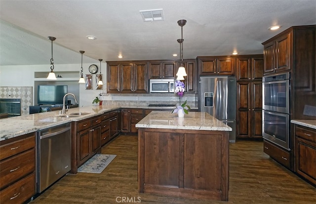 kitchen with a kitchen island, dark wood-type flooring, sink, pendant lighting, and stainless steel appliances