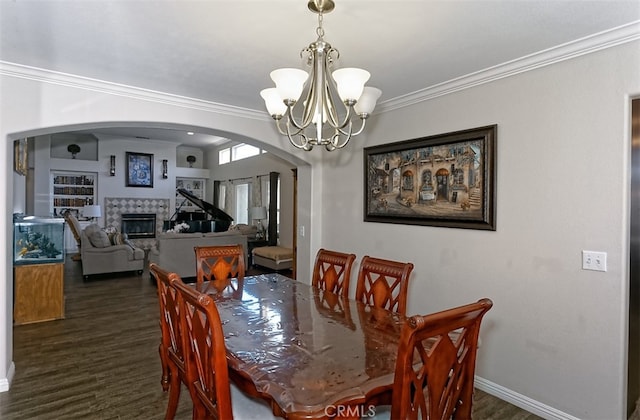 dining area featuring ornamental molding, dark hardwood / wood-style flooring, a fireplace, and an inviting chandelier