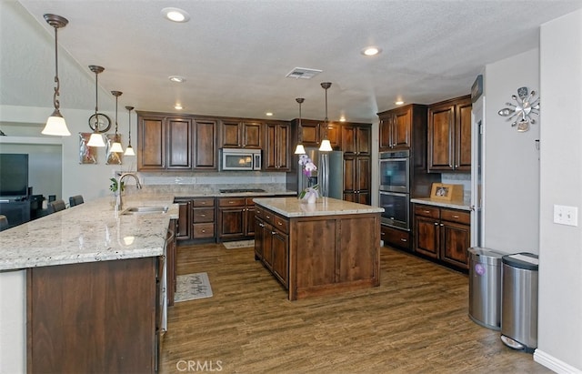 kitchen featuring pendant lighting, appliances with stainless steel finishes, sink, and kitchen peninsula