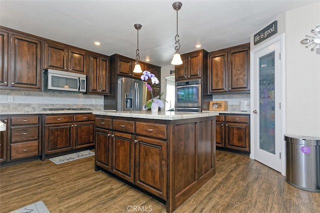 kitchen featuring a center island, dark hardwood / wood-style flooring, stainless steel appliances, pendant lighting, and decorative backsplash