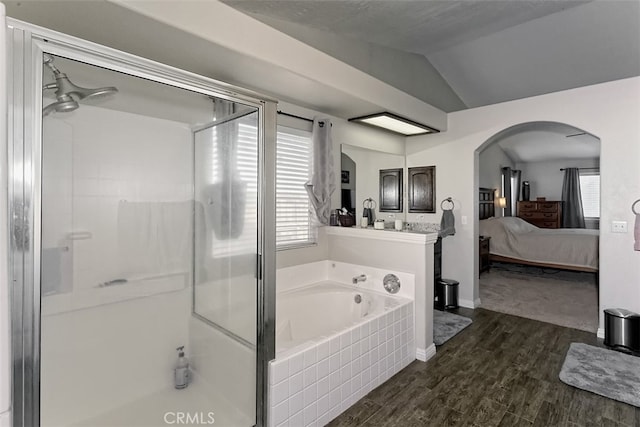 bathroom featuring vaulted ceiling, hardwood / wood-style floors, and plus walk in shower