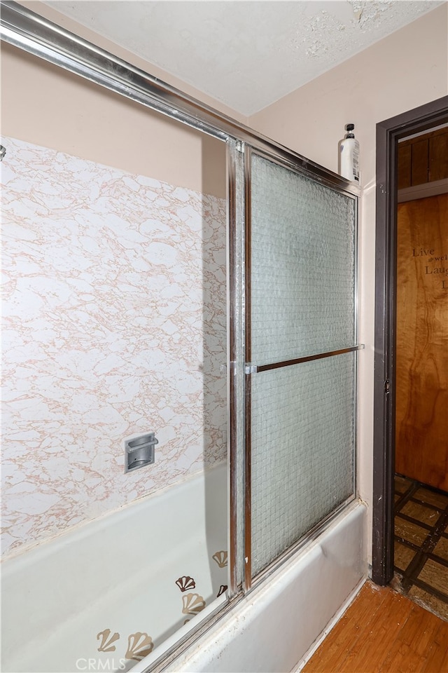 bathroom featuring hardwood / wood-style flooring and shower / bath combination with glass door