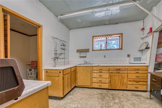 kitchen featuring tile counters, sink, and light colored carpet