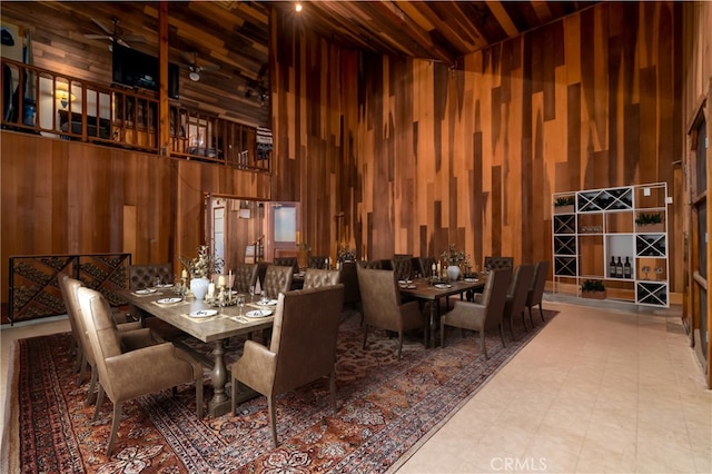 dining space featuring wood ceiling, a high ceiling, and wooden walls