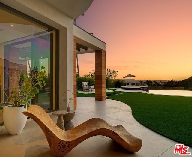 patio terrace at dusk featuring a yard