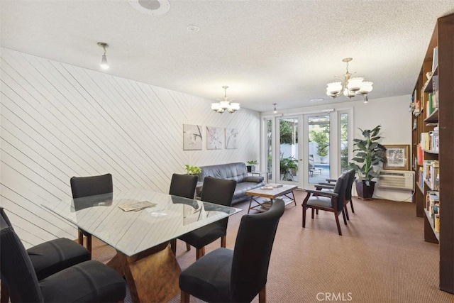 dining space featuring french doors, a chandelier, a textured ceiling, wooden walls, and dark carpet