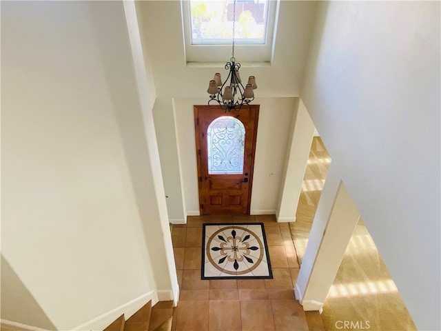 foyer entrance featuring a towering ceiling, light tile patterned floors, and a notable chandelier