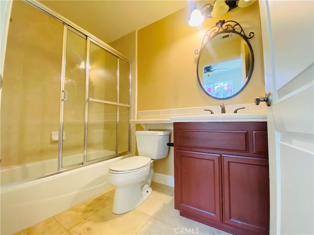 full bathroom with tile patterned floors, bath / shower combo with glass door, vanity, and toilet