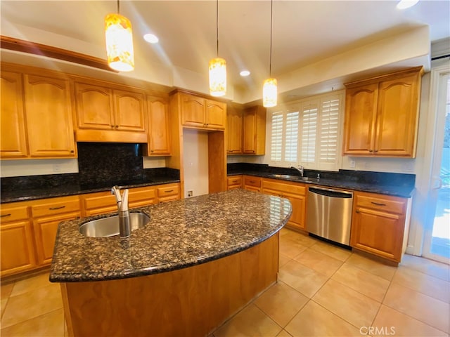 kitchen with pendant lighting, an island with sink, sink, and stainless steel dishwasher