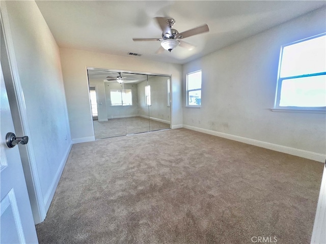 unfurnished bedroom with ceiling fan, light carpet, and a closet