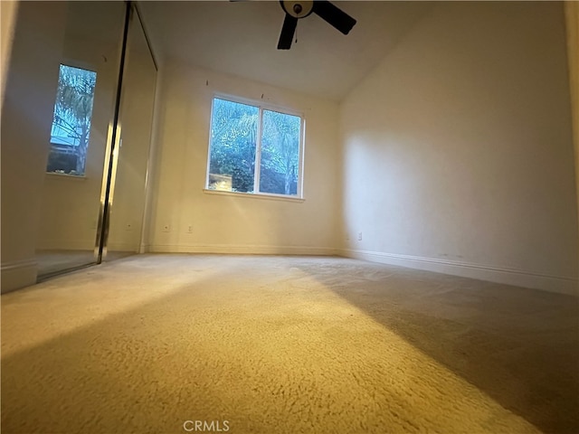 spare room featuring carpet floors, lofted ceiling, and ceiling fan