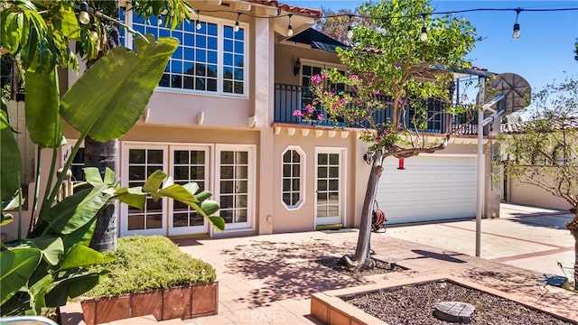 rear view of property featuring a balcony and a garage