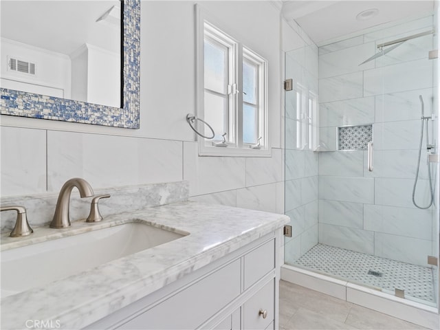 bathroom with tile walls, tile patterned floors, walk in shower, and vanity