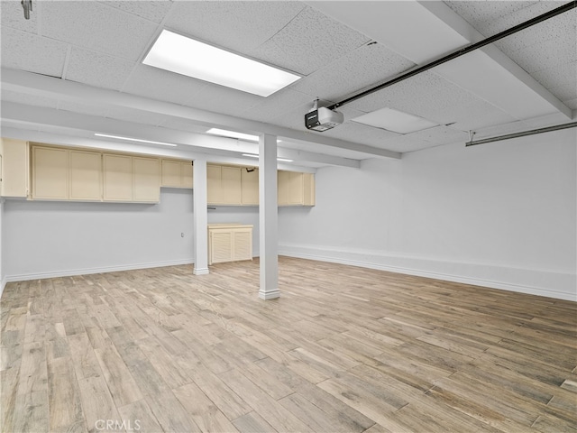 basement featuring light wood-type flooring and a paneled ceiling