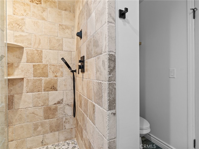 bathroom featuring a tile shower and toilet