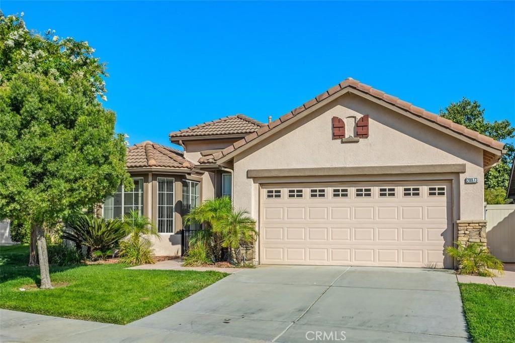 mediterranean / spanish-style home with a garage and a front lawn