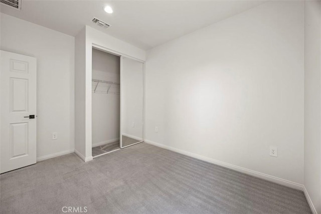 unfurnished bedroom featuring light carpet and a closet