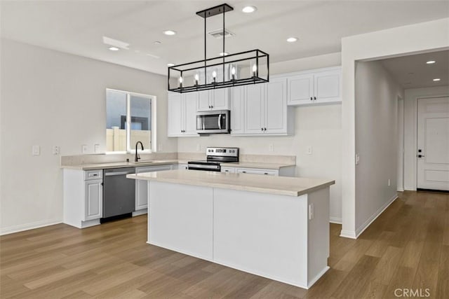 kitchen featuring pendant lighting, a center island, stainless steel appliances, and white cabinetry