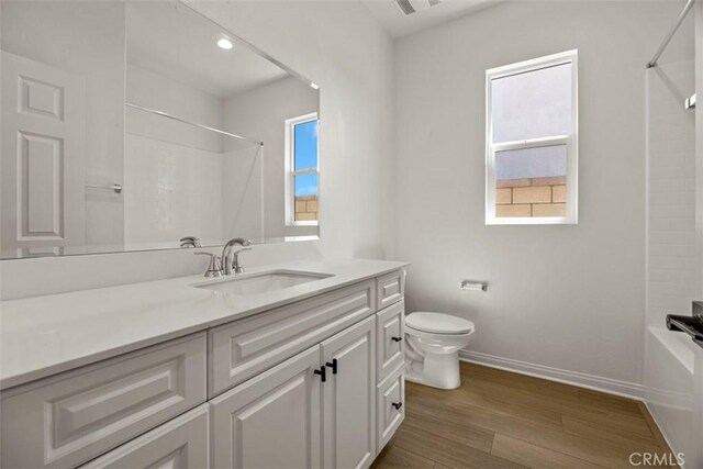 full bathroom with hardwood / wood-style floors, plenty of natural light, toilet, and vanity