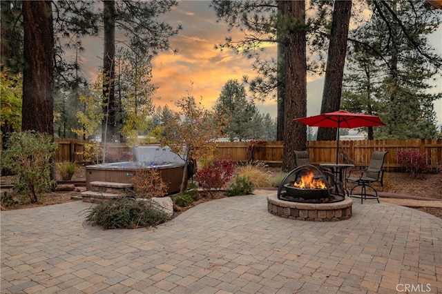 patio terrace at dusk featuring a hot tub and a fire pit