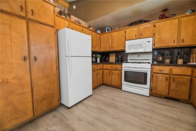 kitchen with light hardwood / wood-style floors, white appliances, and tasteful backsplash