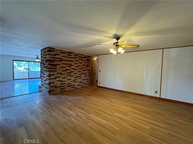 interior space featuring hardwood / wood-style floors, ceiling fan, and brick wall