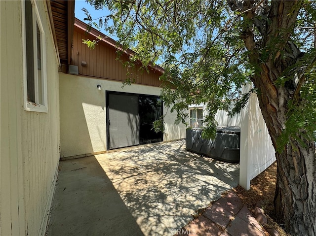 back of property with a jacuzzi and a patio area