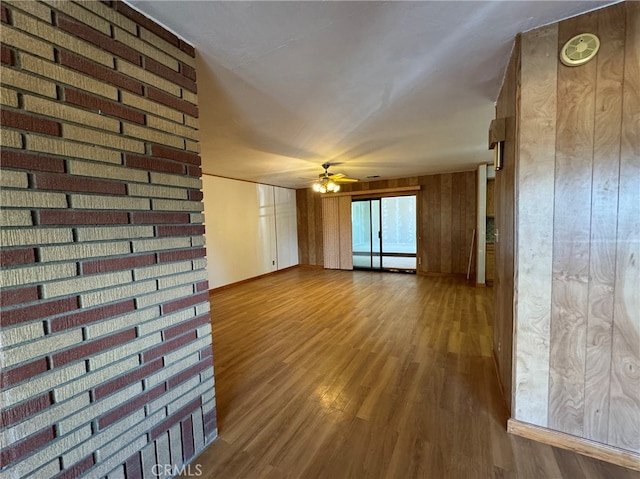 unfurnished room with ceiling fan, hardwood / wood-style flooring, and wood walls