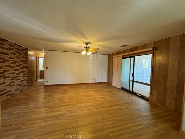 spare room featuring wooden walls, ceiling fan, and hardwood / wood-style floors